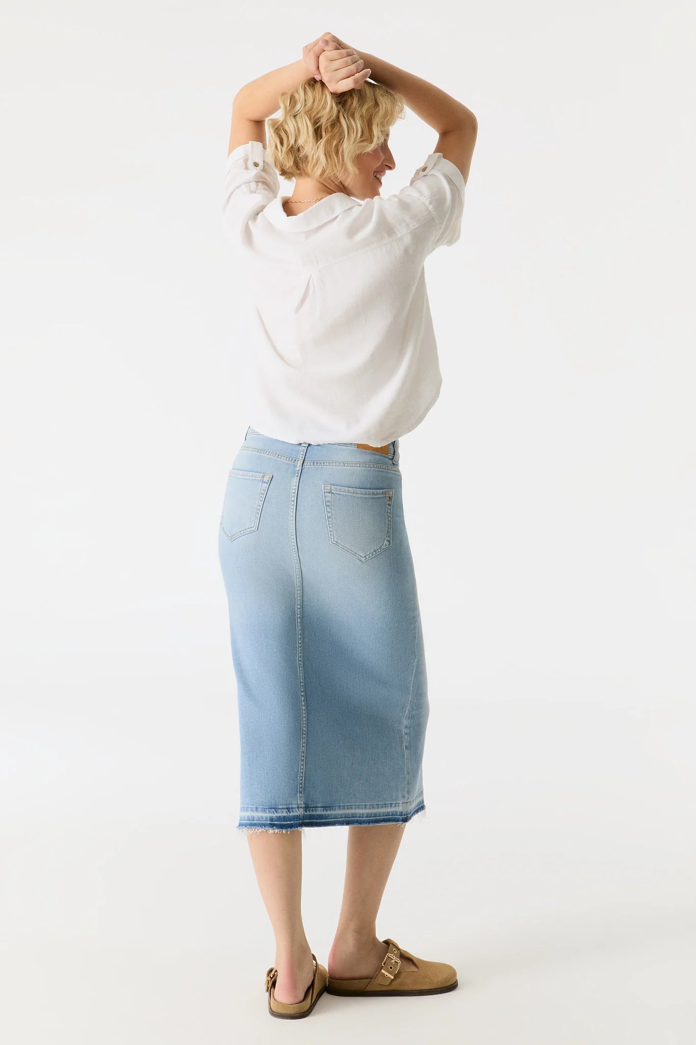 Person wearing a white sweatshirt and light blue denim skirt on a white background