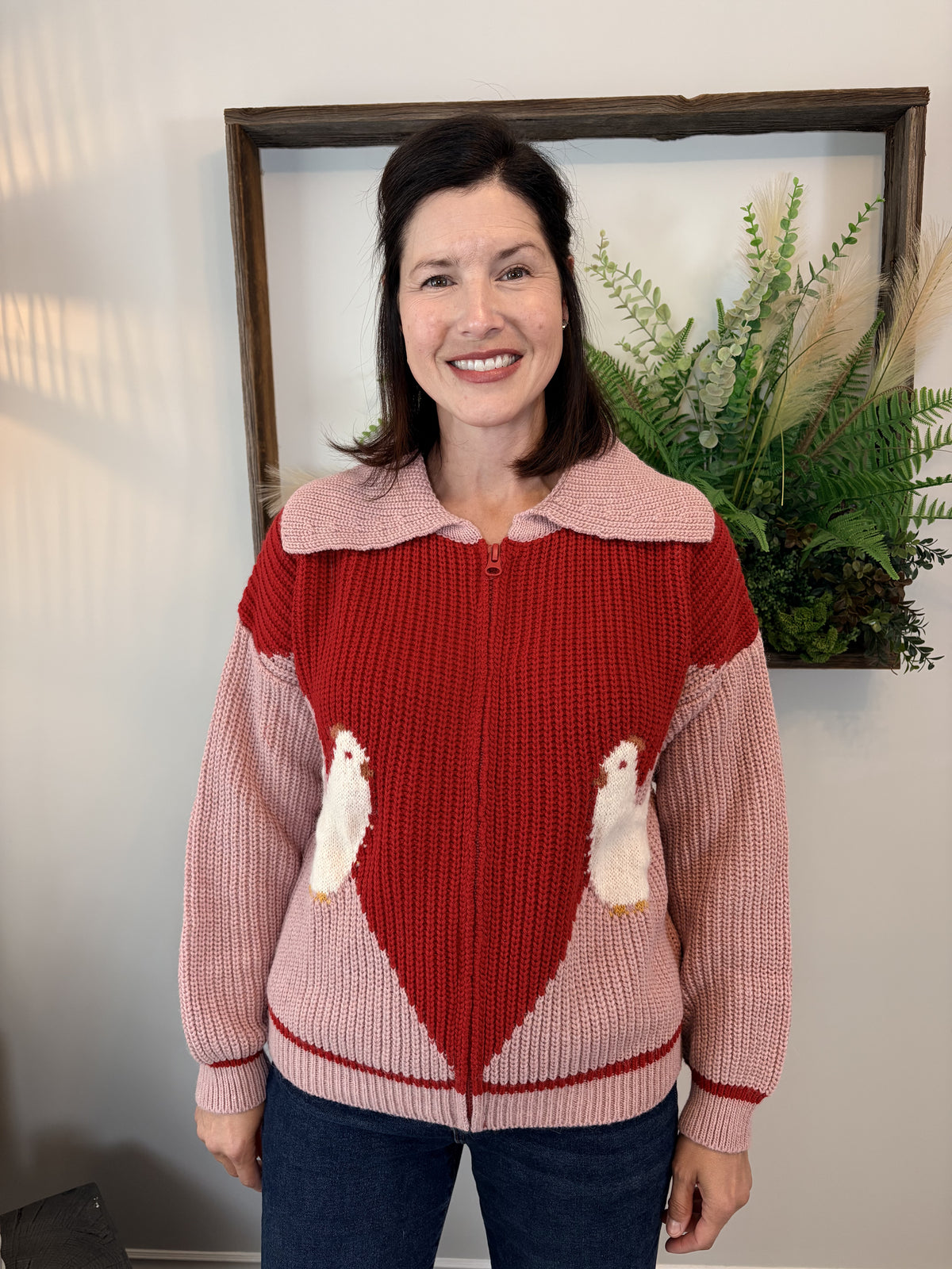 Woman wearing pink and red colour-block Farm Cardigan by Dr Bloom with playful chicken knit detail, front view