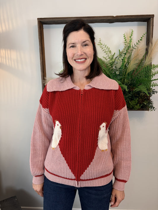 Woman wearing pink and red colour-block Farm Cardigan by Dr Bloom with playful chicken knit detail, front view