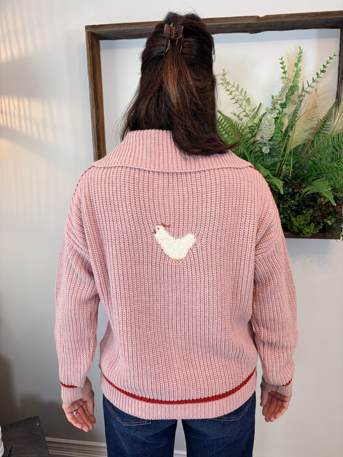 Woman wearing pink and red colour-block Farm Cardigan by Dr Bloom with playful chicken knit detail, front view