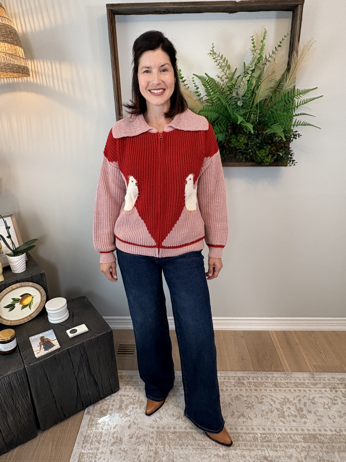 Woman wearing pink and red colour-block Farm Cardigan by Dr Bloom with playful chicken knit detail, front view