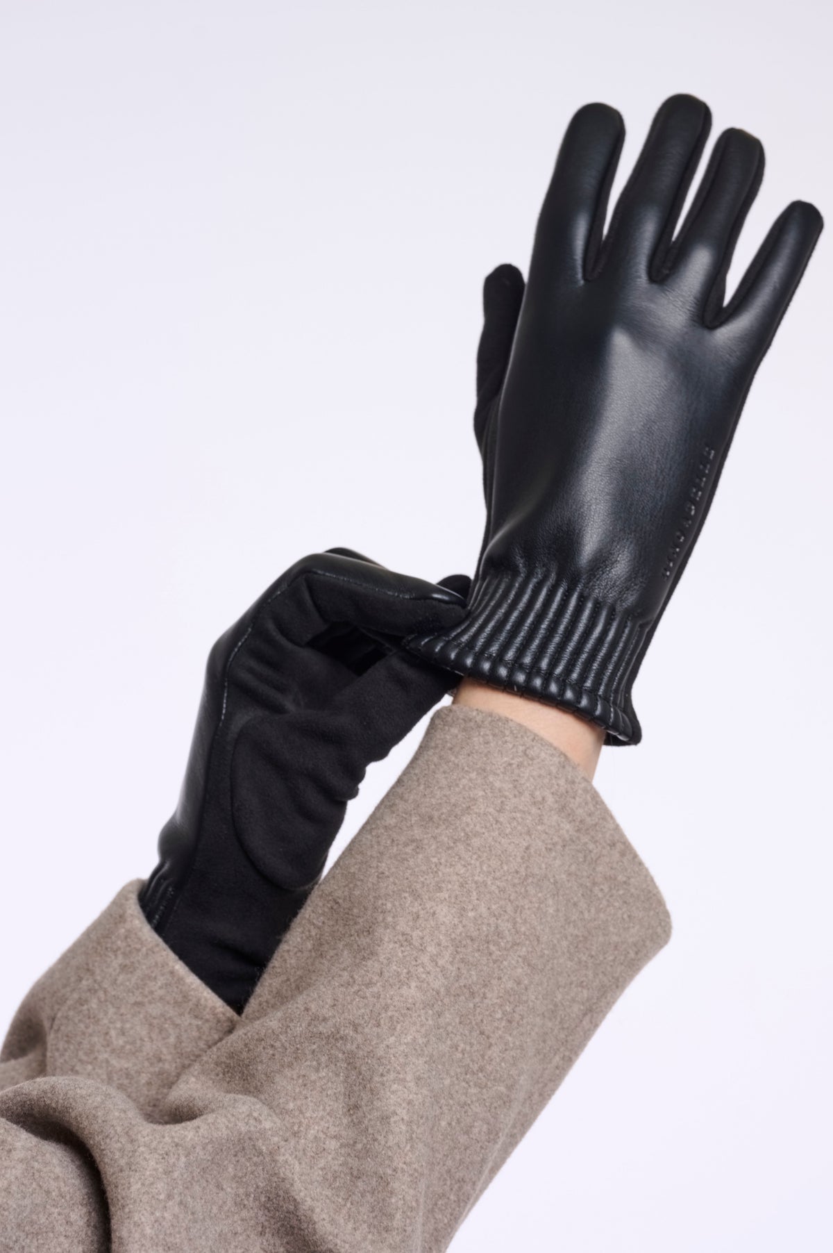 Rino & Pelle Fidelia black faux leather gloves with suede-feel palm and ribbed cuff, worn with a taupe wool coat