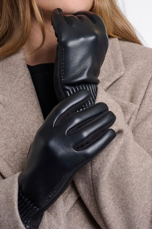 Rino & Pelle Fidelia black faux leather gloves with suede-feel palm and ribbed cuff, worn with a taupe wool coat