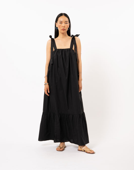 The Ceylia Dress in black by FRNCH is a versatile piece for any summertime occasion. With its fluid and flowing design, this long dress is ideal for any occasion. You can wear it tied around your shoulders or in a charming sailor style. Embrace the multiple ways to wear this tie band dress and create your perfect look.