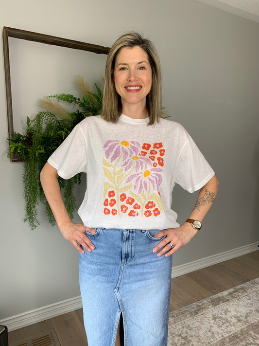Elevate your wardrobe with the the Korner from Paris White Floral Graphic Tee, where effortless style meets Parisian charm. Crafted with soft, breathable fabric, this tee boasts a stunning floral pattern in hues of lavender, orange, and charteuse green, reminiscent of a stroll through a Parisian garden. Whether you're pairing it with your favourite denim for a casual brunch or dressing it up with a chic skirt for a night out, this tee adds a touch of sophistication to any ensemble.