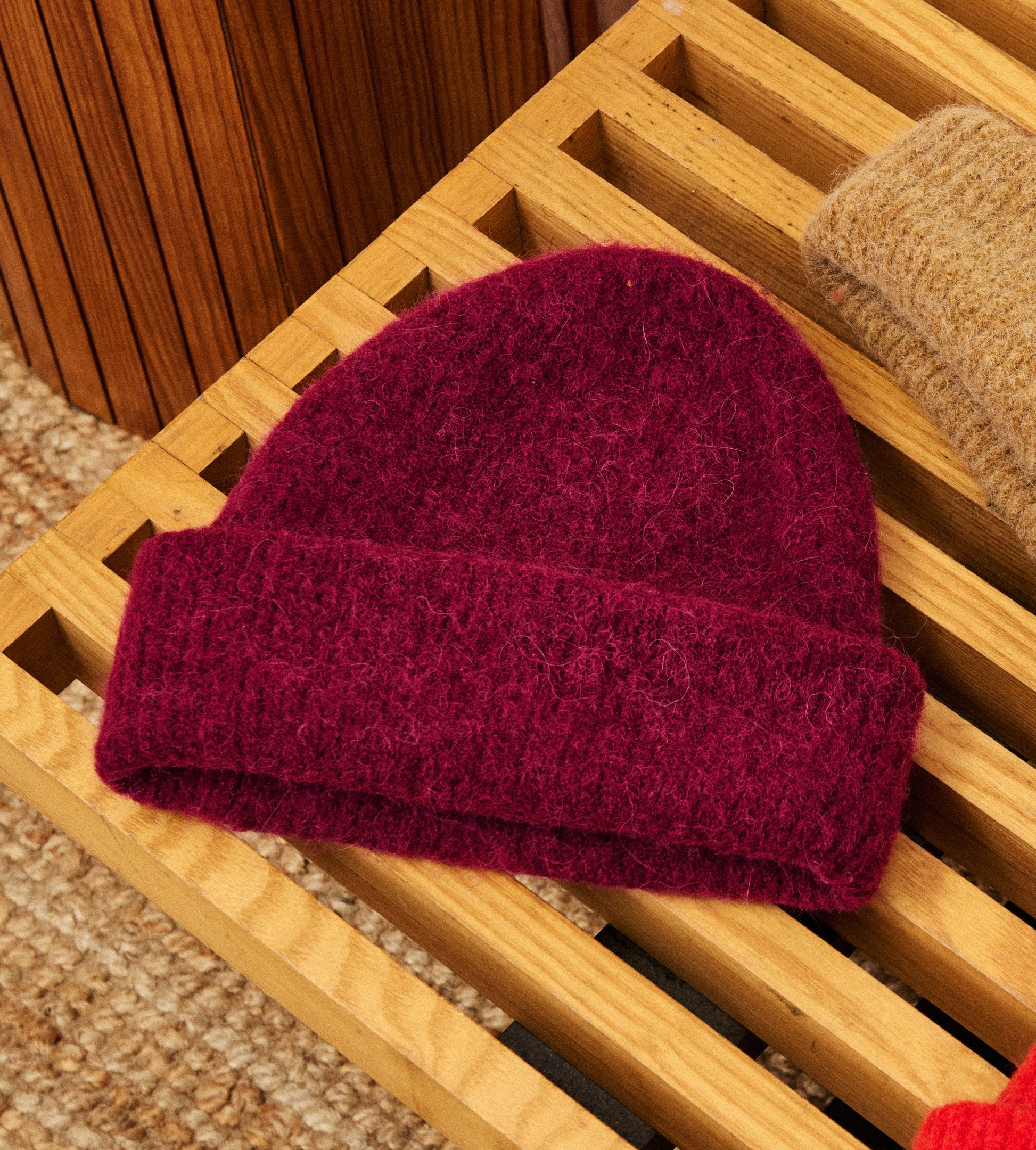 Maroon knit beanie on a wooden surface