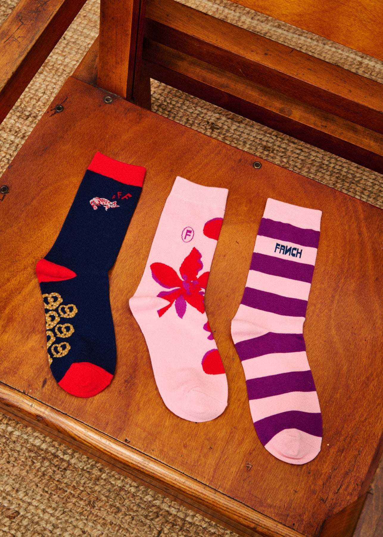 Three pairs of socks with different designs on a wooden chair.