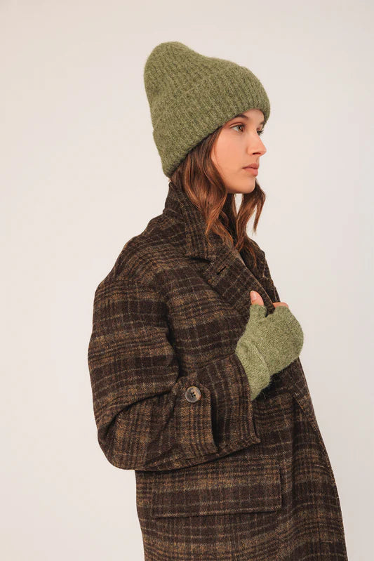 Person wearing a brown plaid coat, green beanie, and matching gloves on a white background