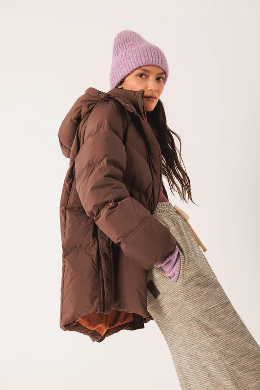 Person wearing a brown puffer coat and purple beanie on a white background