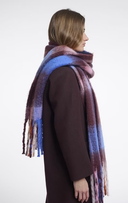 Woman wearing the Rino & Pelle Hibbe oversized check scarf in burgundy, blue and pink with fringe ends, styled with a burgundy wool coat