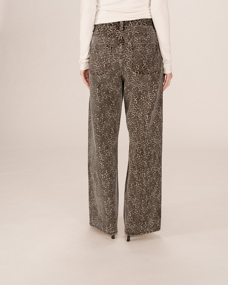 Person wearing leopard patterned pants on a plain background