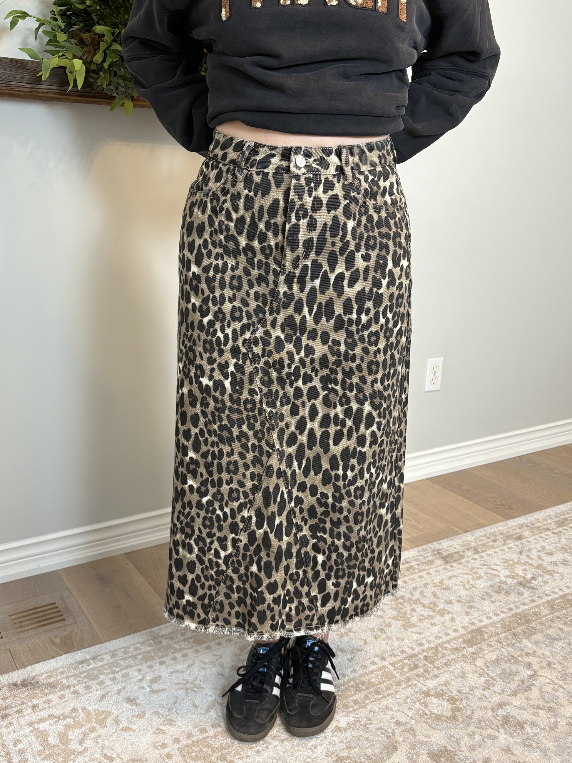 Person wearing a black sweatshirt and leopard print skirt indoors.