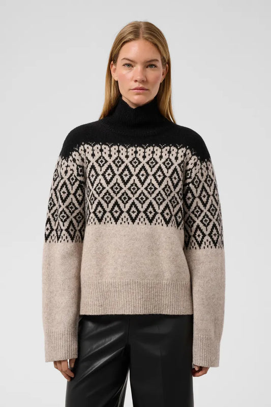 Woman wearing black and oatmeal Fair Isle turtleneck sweater by Soaked in Luxury, paired with black leather pants