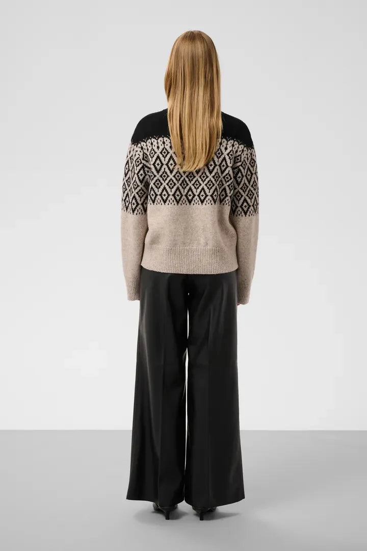 Woman wearing black and oatmeal Fair Isle turtleneck sweater by Soaked in Luxury, paired with black leather pants