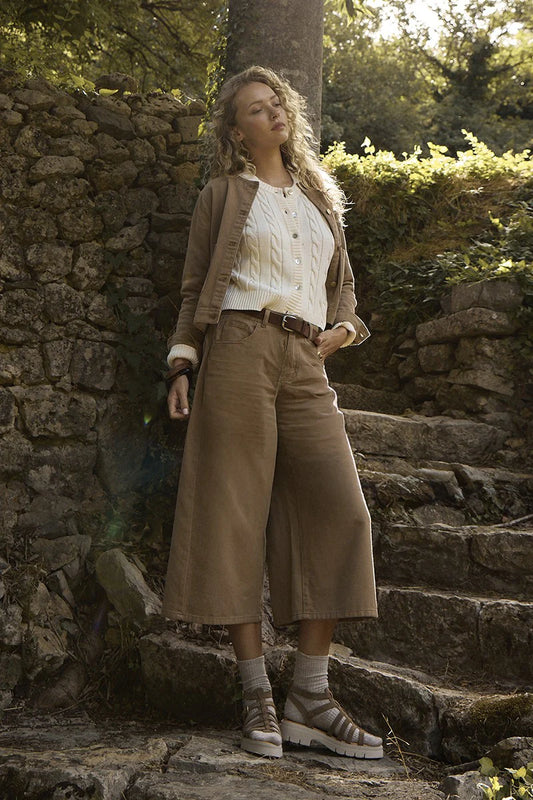 Woman standing in a natural setting with stone wall and steps