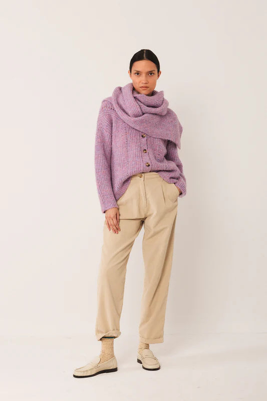 Person wearing a purple sweater and beige pants on a white background