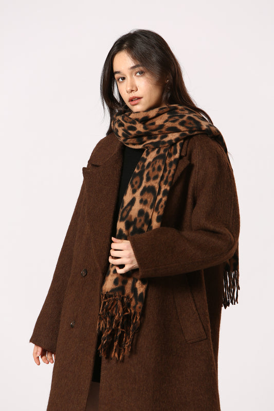 Woman wearing a brown coat and leopard print scarf on a white background