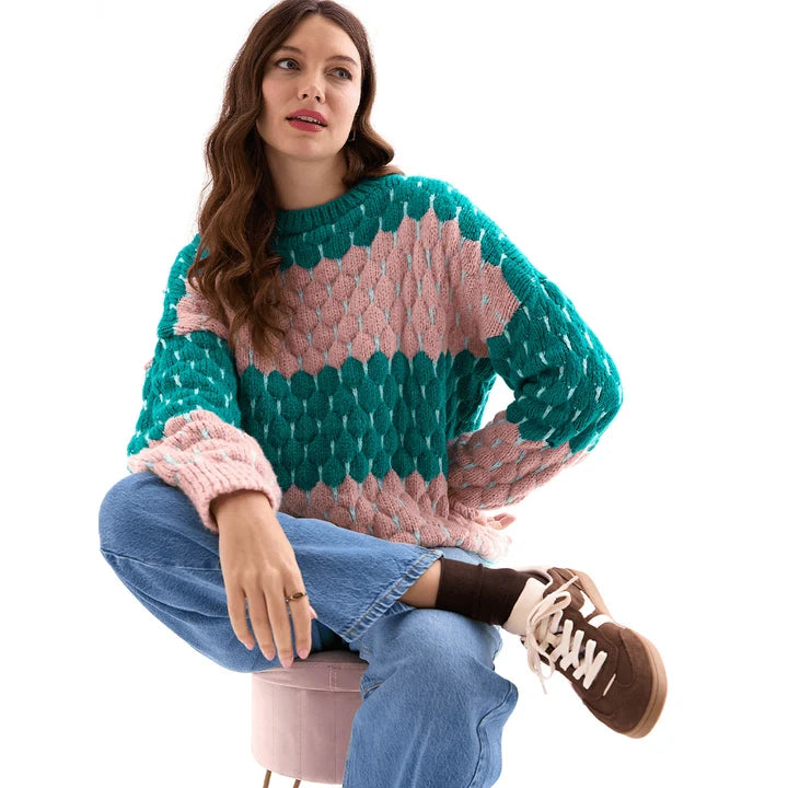Woman wearing the Marissa green and pink bubble stitch sweater with balloon sleeves and jeans