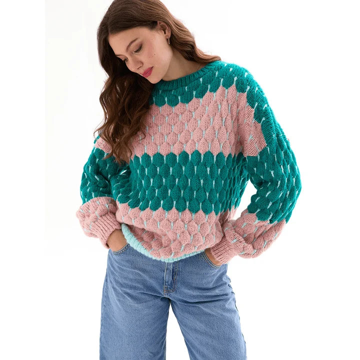 Woman wearing the Marissa green and pink bubble stitch sweater with balloon sleeves and jeans