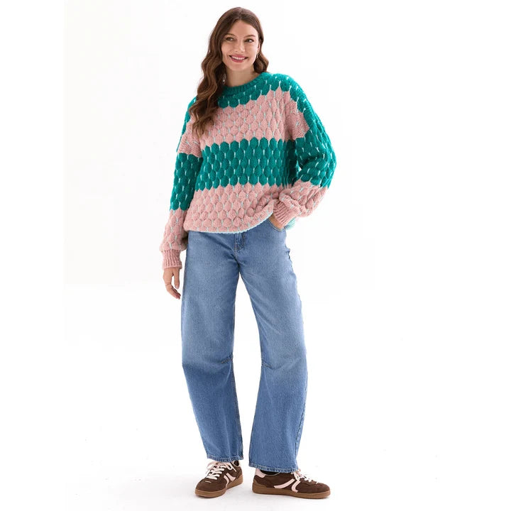 Woman wearing the Marissa green and pink bubble stitch sweater with balloon sleeves and jeans