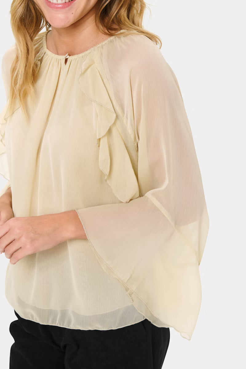 Woman wearing a light beige blouse with ruffled sleeves on a white background