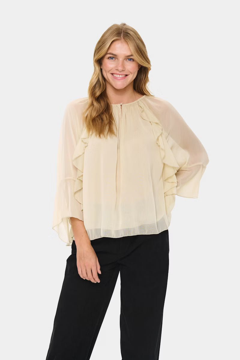 Woman wearing a beige blouse with ruffled sleeves on a white background