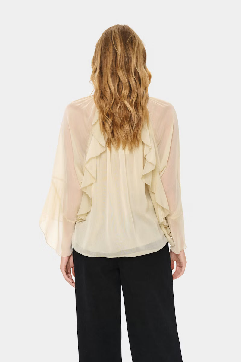 Woman wearing a beige blouse with ruffled sleeves on a white background