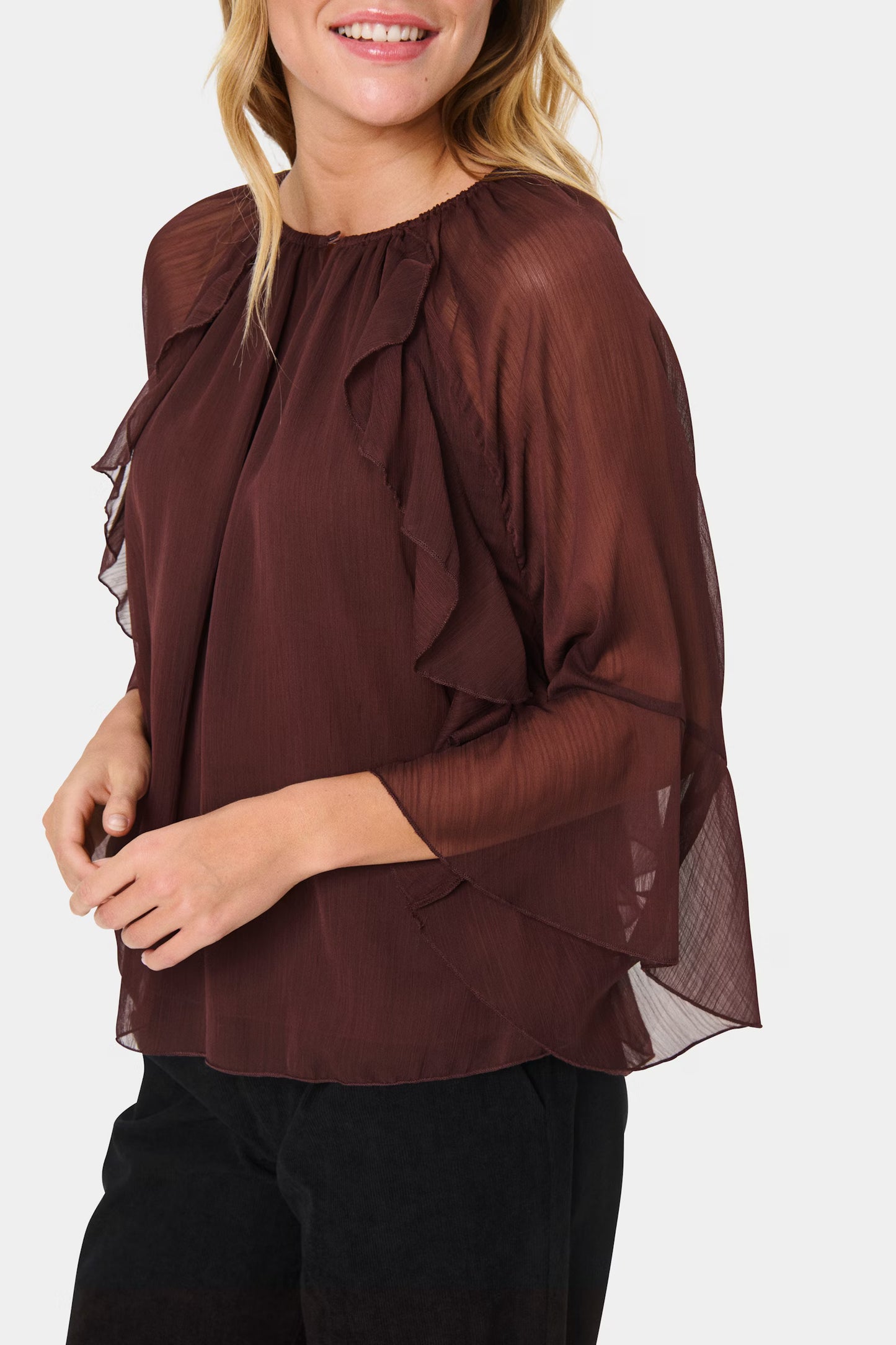 Woman wearing a brown ruffled blouse against a white background