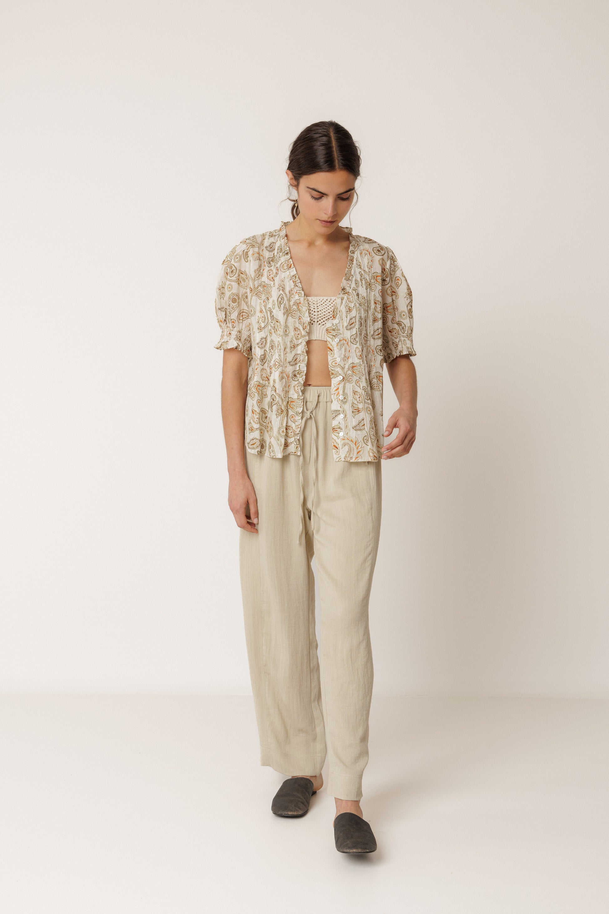 Woman wearing a floral top and beige pants on a white background