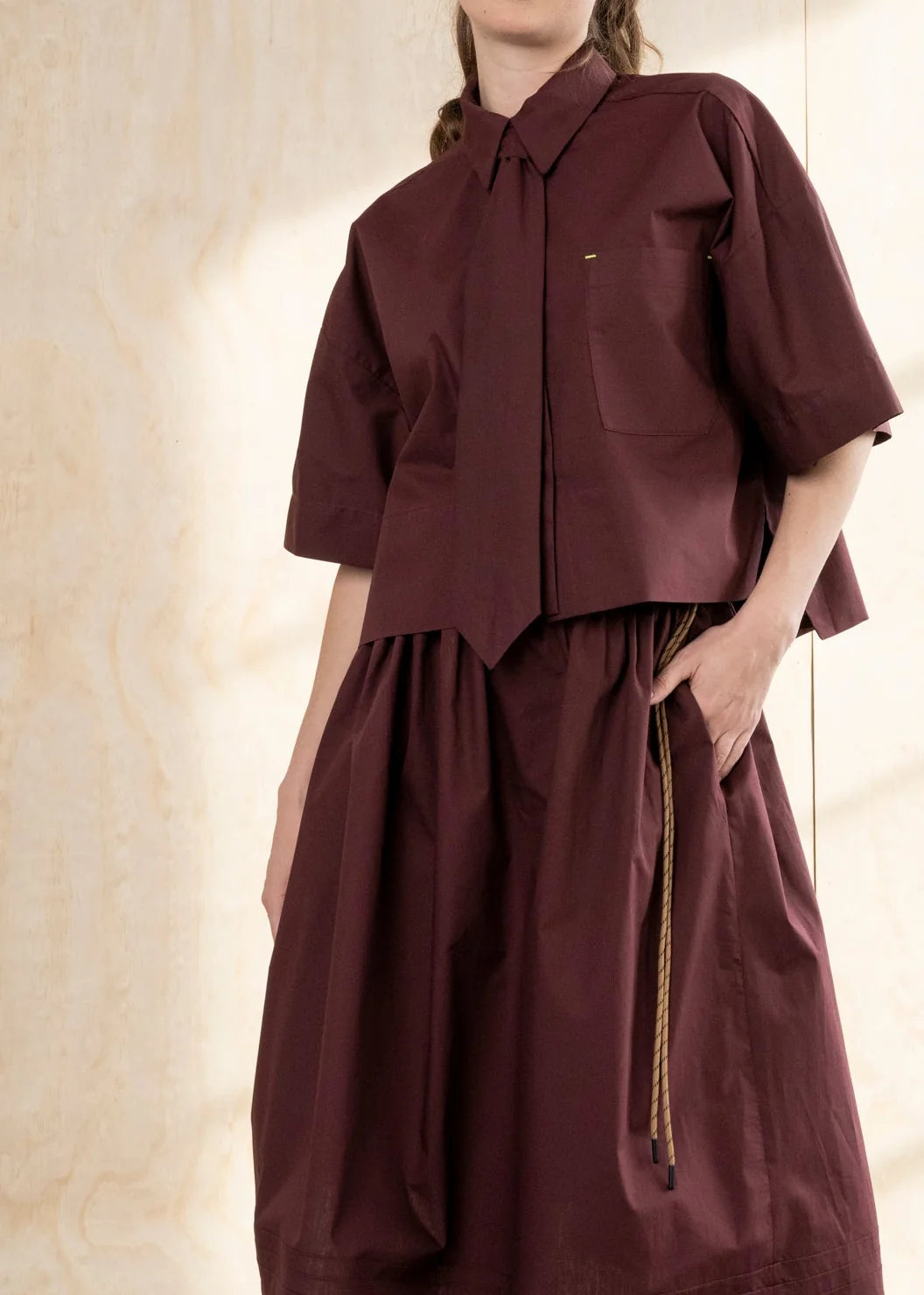 Burgundy cropped cotton poplin shirt with point collar and neon bar tack accents by Bodybag by Jude