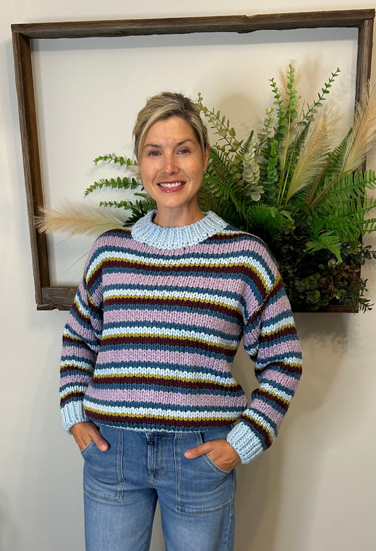 Get ready to add a dose of colour to your wardrobe with our Striped Multicolour Sweater by The Korner. This fun crew neck sweater features stripes in different widths, creating a cool and playful pattern in shades of blue, purple, and a pop of green. 