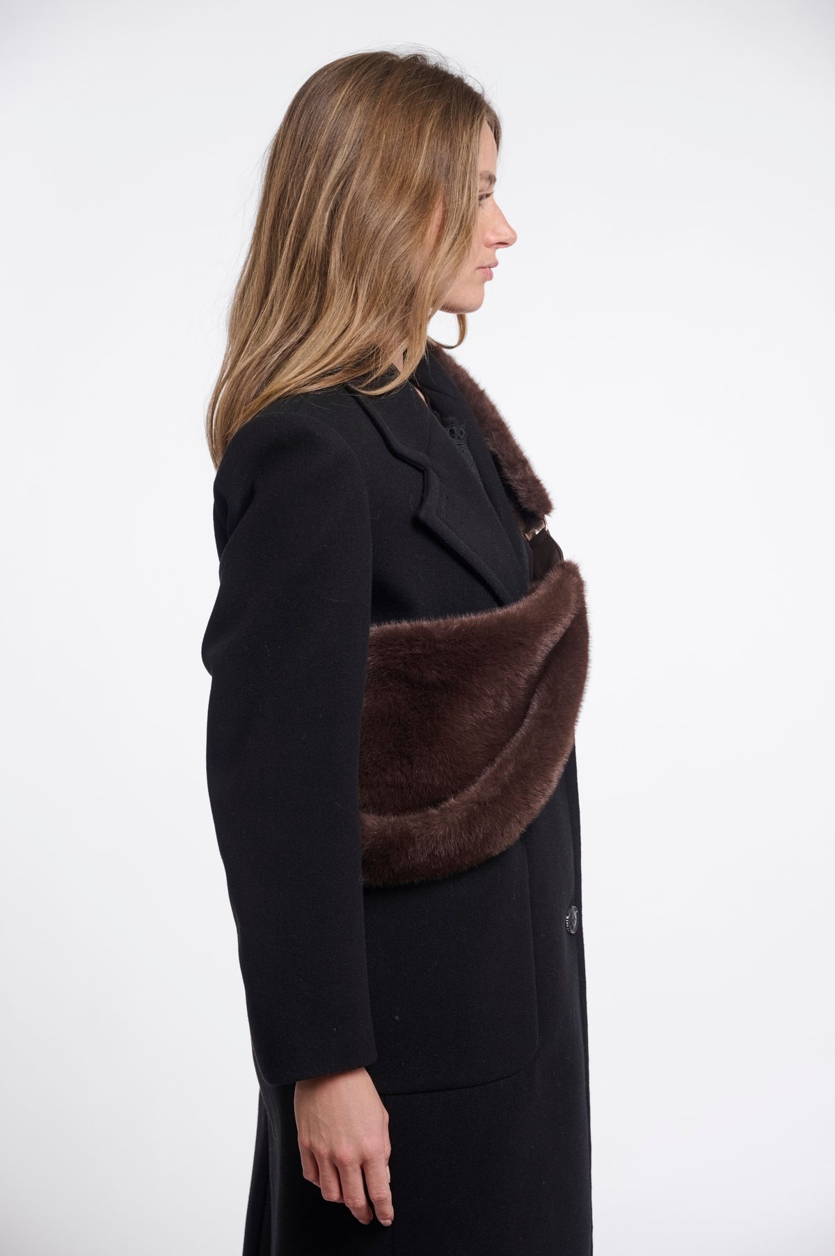 Rino & Pelle Nayla chocolate brown faux fur crescent crossbody bag worn across the body over a black wool coat