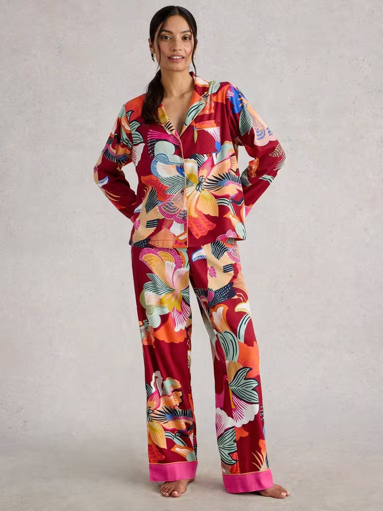 Woman wearing a colorful floral pajama set against a plain background