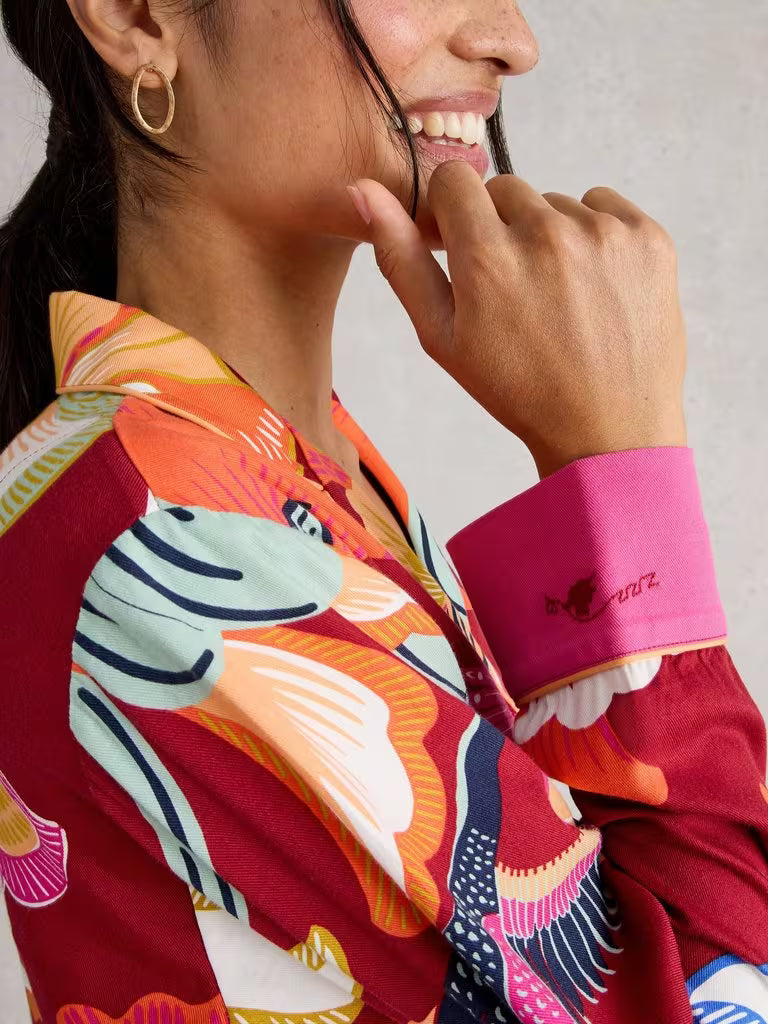 Person wearing a colorful shirt with a zebra design and a pink cuff, smiling.