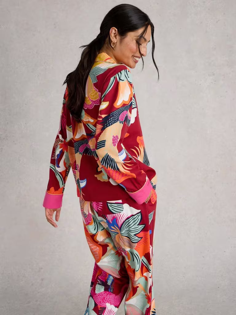 Woman wearing a colorful outfit with a patterned design on a plain background