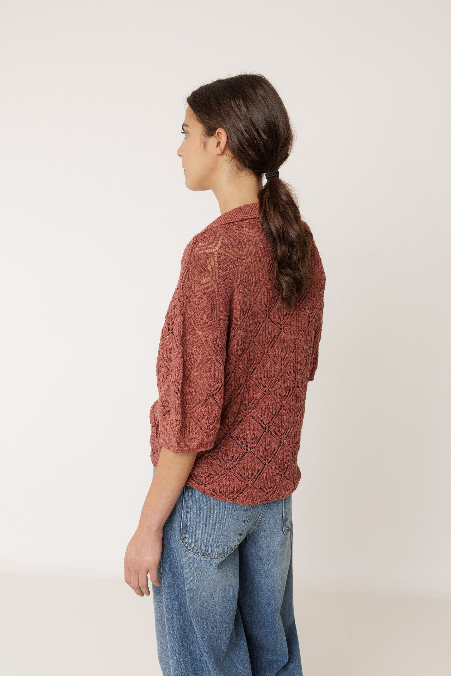 Woman wearing a brown knitted sweater and blue jeans on a white background