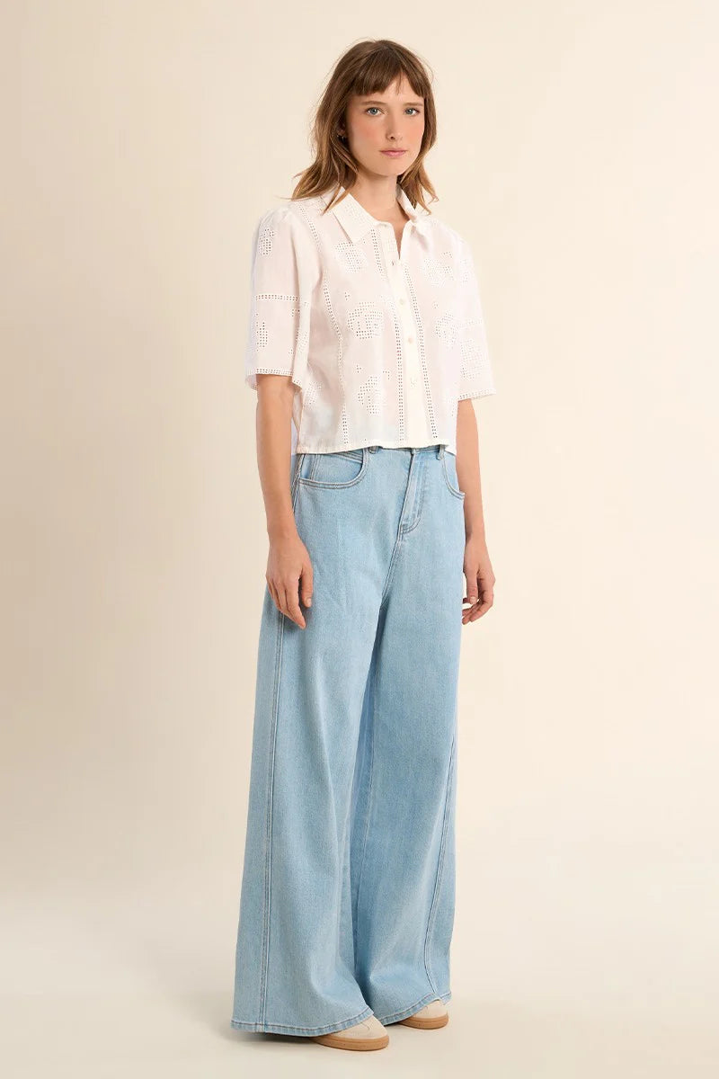 Woman wearing a white blouse and light blue jeans on a beige background