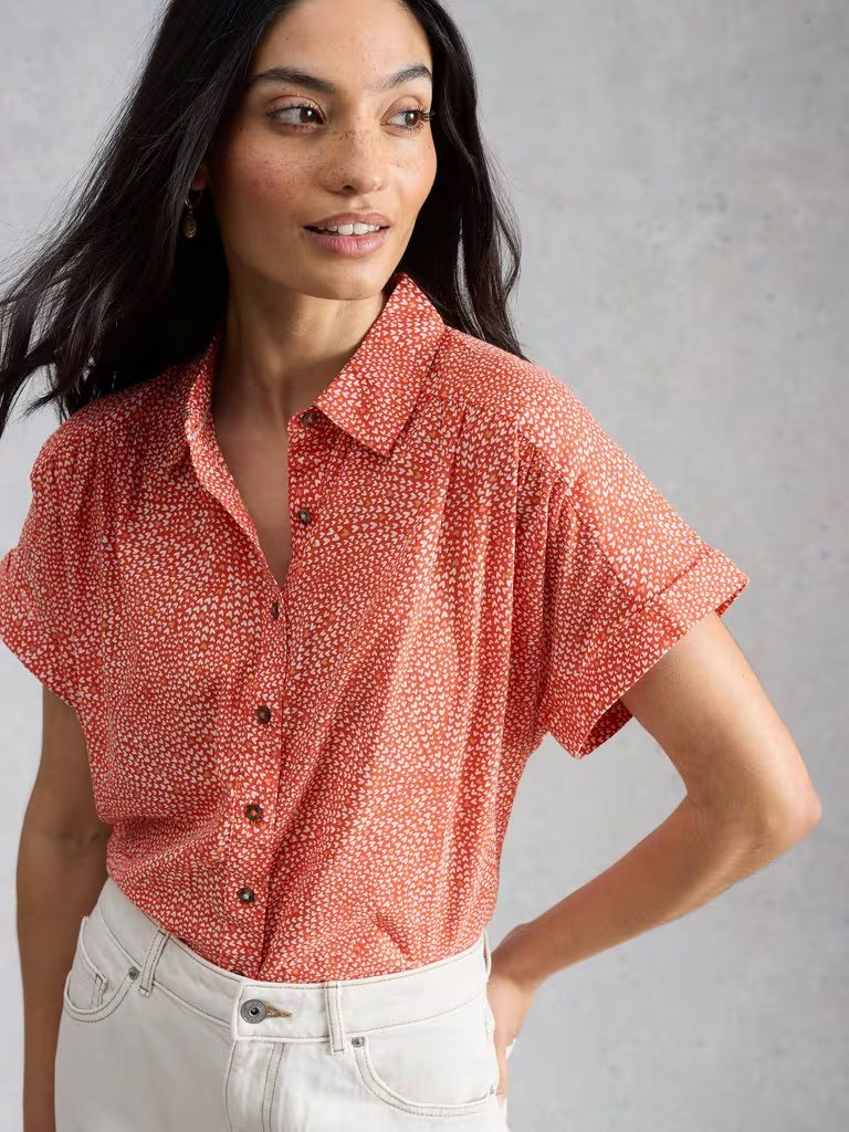 Woman wearing a red patterned shirt against a gray background