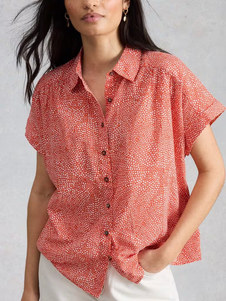 Woman wearing a red patterned blouse against a gray background