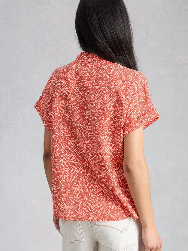 Person wearing a red patterned shirt against a gray background