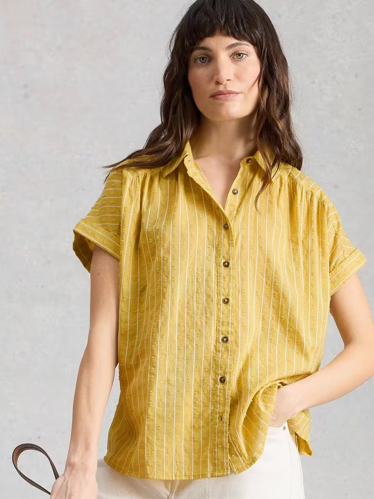 Woman wearing a yellow striped shirt against a light gray background