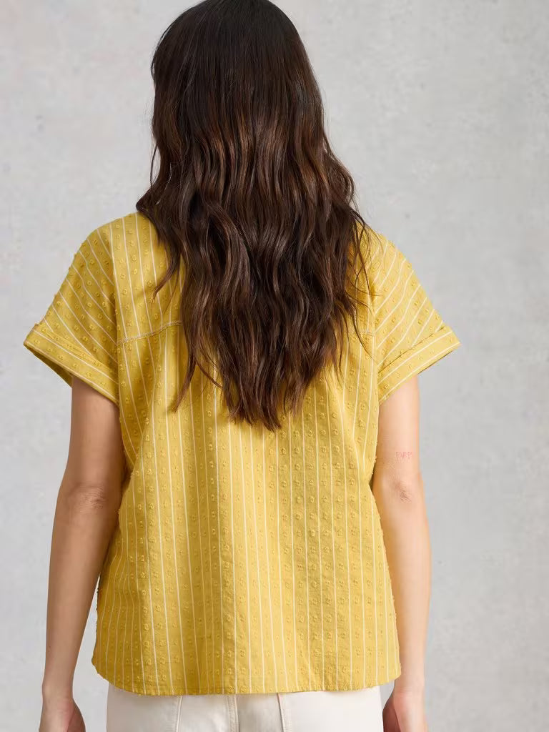Person wearing a yellow striped shirt against a gray background