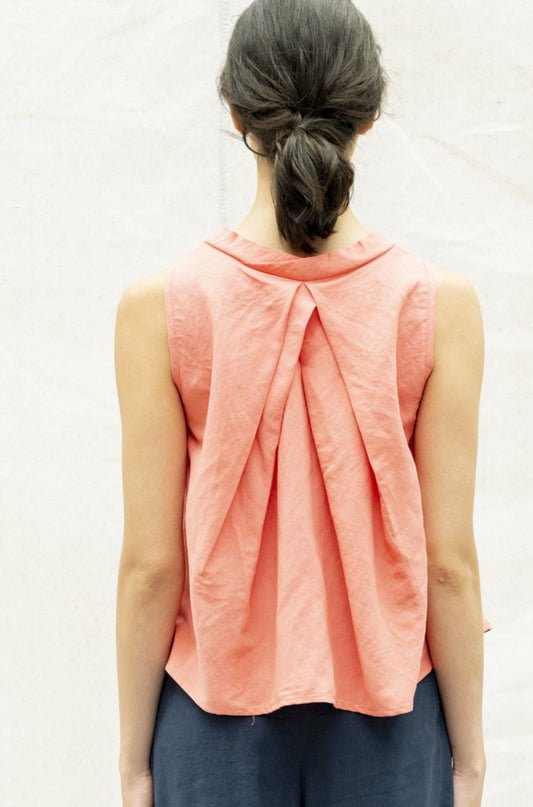 The Pacifica Top by BODYBAG by Jude features a sleeveless square design with a pleated back and a wide, layered silhouette for added movement. It sits comfortably above the waist, creating a flattering look. Made with a blend of viscose and linen, this top boasts a delicate and airy texture in a stunning salmon shade.