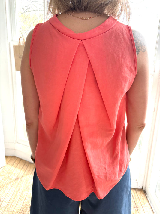 The Pacifica Top by BODYBAG by Jude features a sleeveless square design with a pleated back and a wide, layered silhouette for added movement. It sits comfortably above the waist, creating a flattering look. Made with a blend of viscose and linen, this top boasts a delicate and airy texture in a stunning salmon shade.