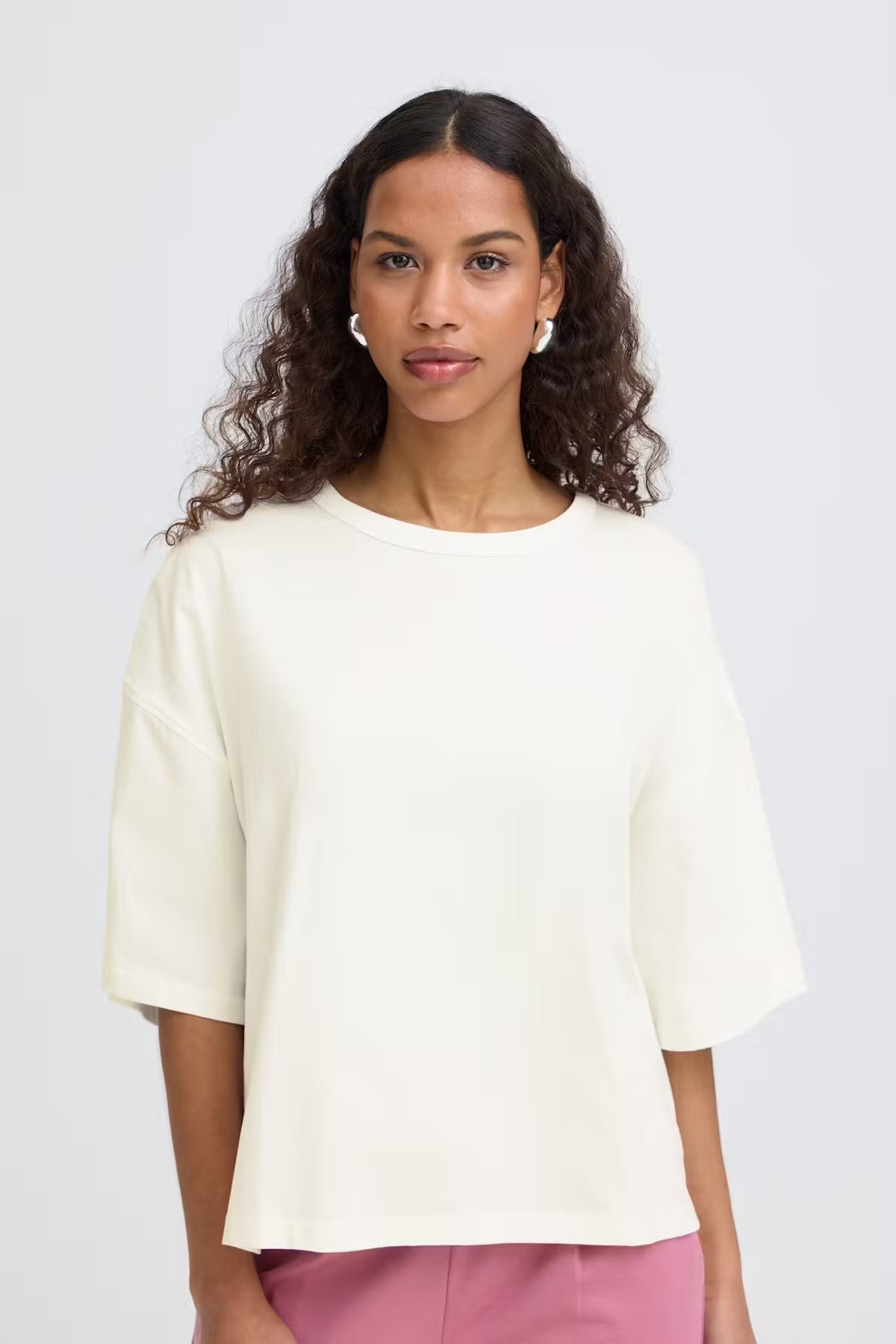 Woman wearing a light-colored blouse against a plain background