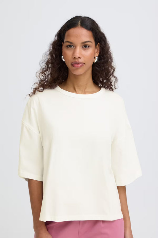 Woman wearing a light-colored blouse against a plain background