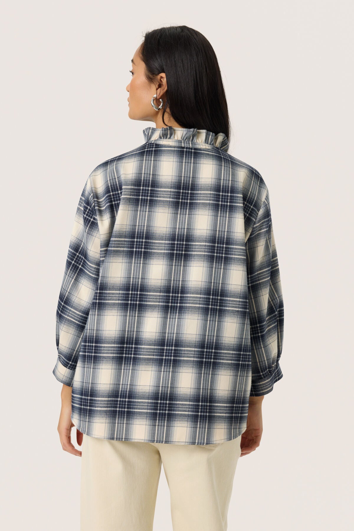 Person wearing a black and white plaid shirt on a plain background