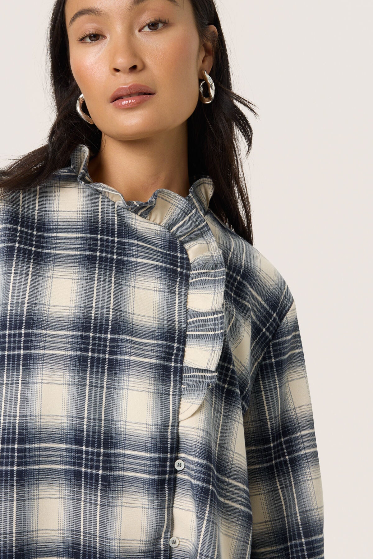 Woman wearing a blue and white plaid shirt against a plain background