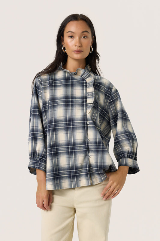 Woman wearing a blue and white plaid shirt with a white background