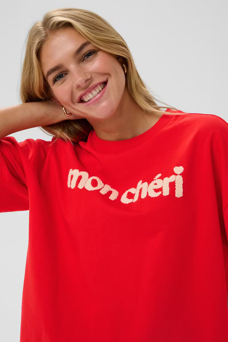 Woman wearing a red 'mon cheri' t-shirt against a plain background